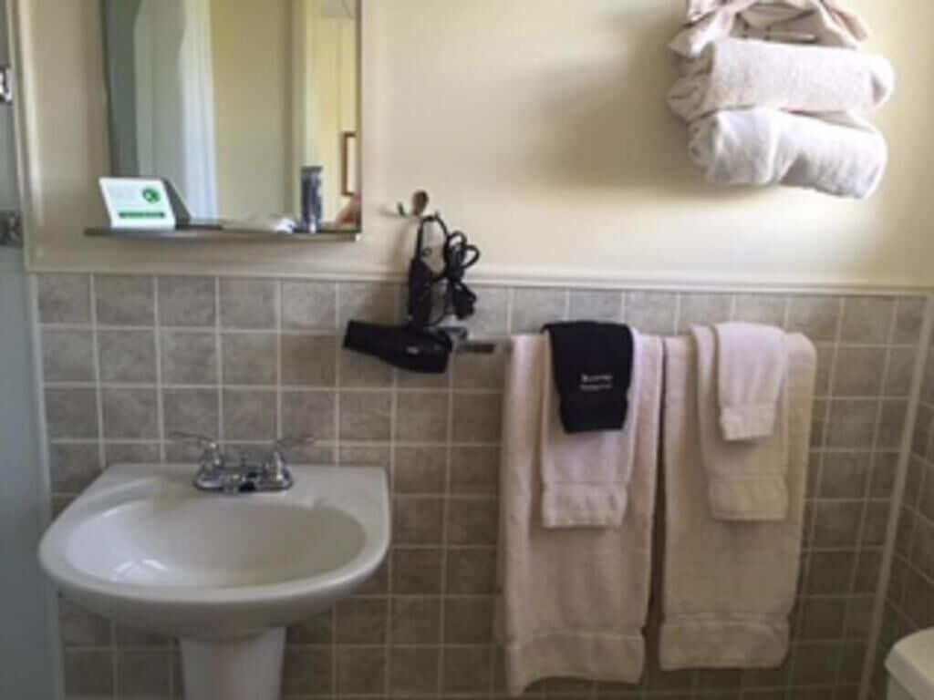 Une salle de bain avec un lavabo, un porte-serviettes avec des serviettes et un miroir.