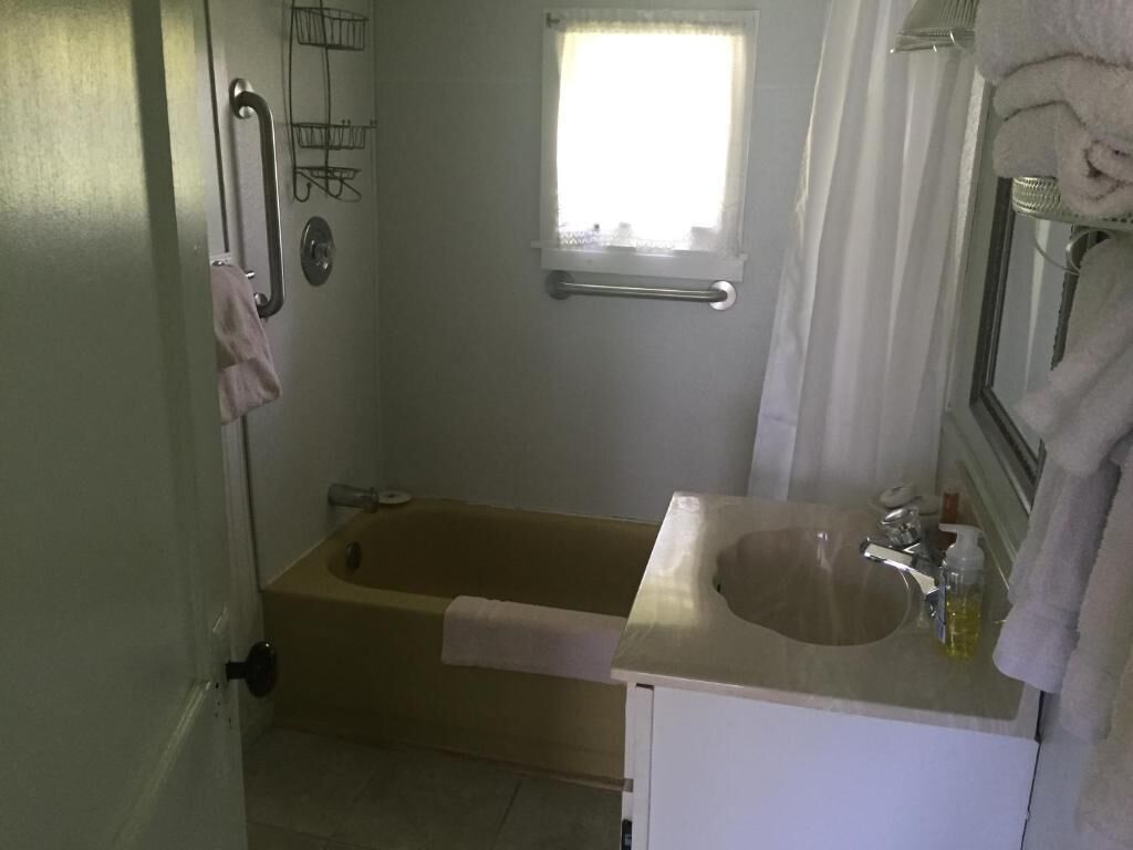 A bathroom with a bathtub, a sink, a window, and a towel rack.