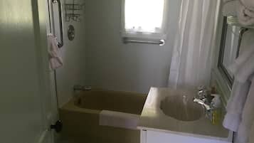 A bathroom with a bathtub, a sink, a window, and a towel rack.