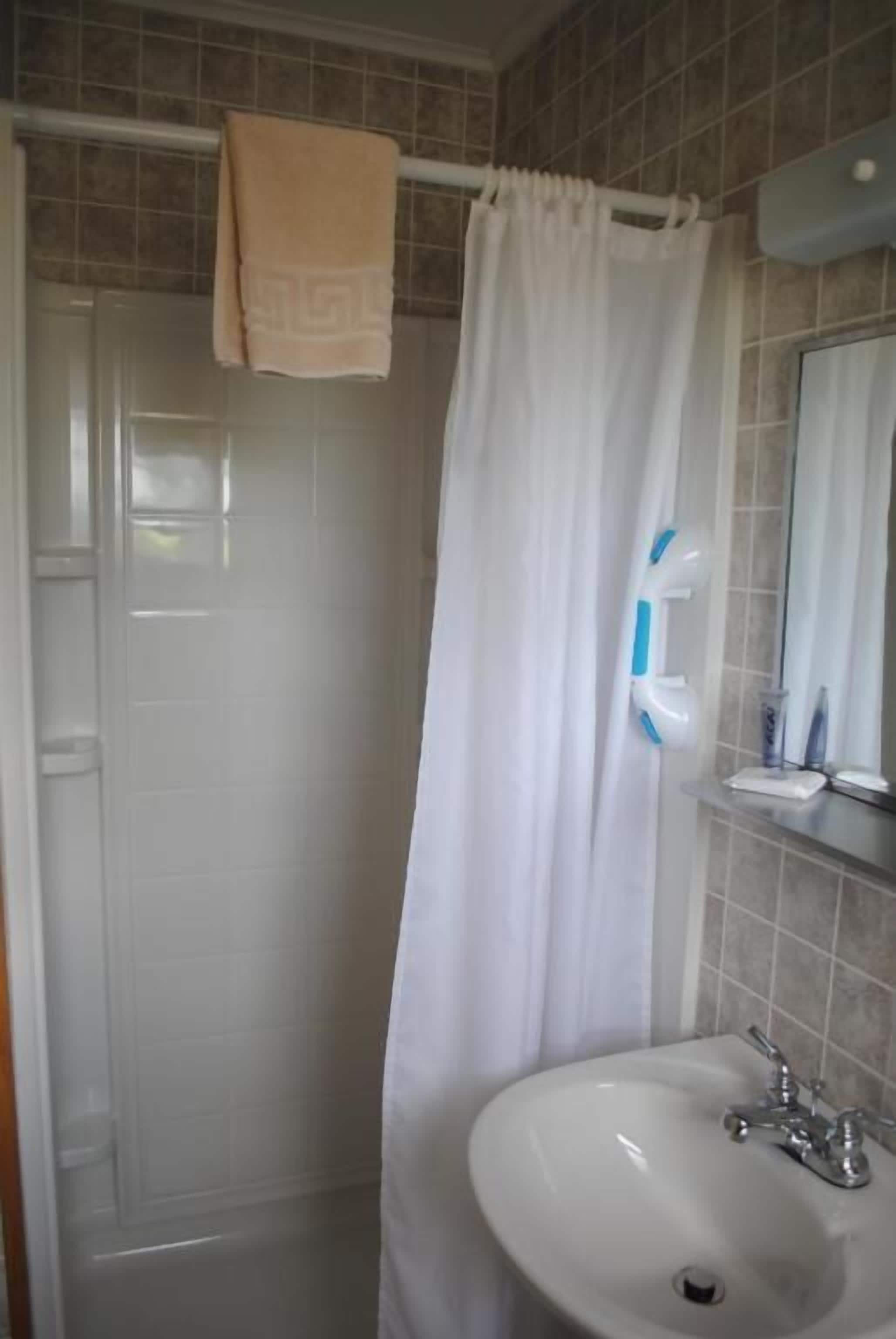 Ein Badezimmer mit einem weißen Waschbecken, einem Spiegel und einer Duschvorhang.