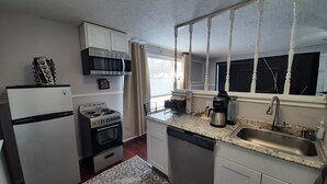 Una cocina compacta con refrigerador, estufa, microondas y cafetera.