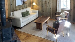 Un interior rústico con techo de madera, chimenea, sofá, mesa de centro y una silla.