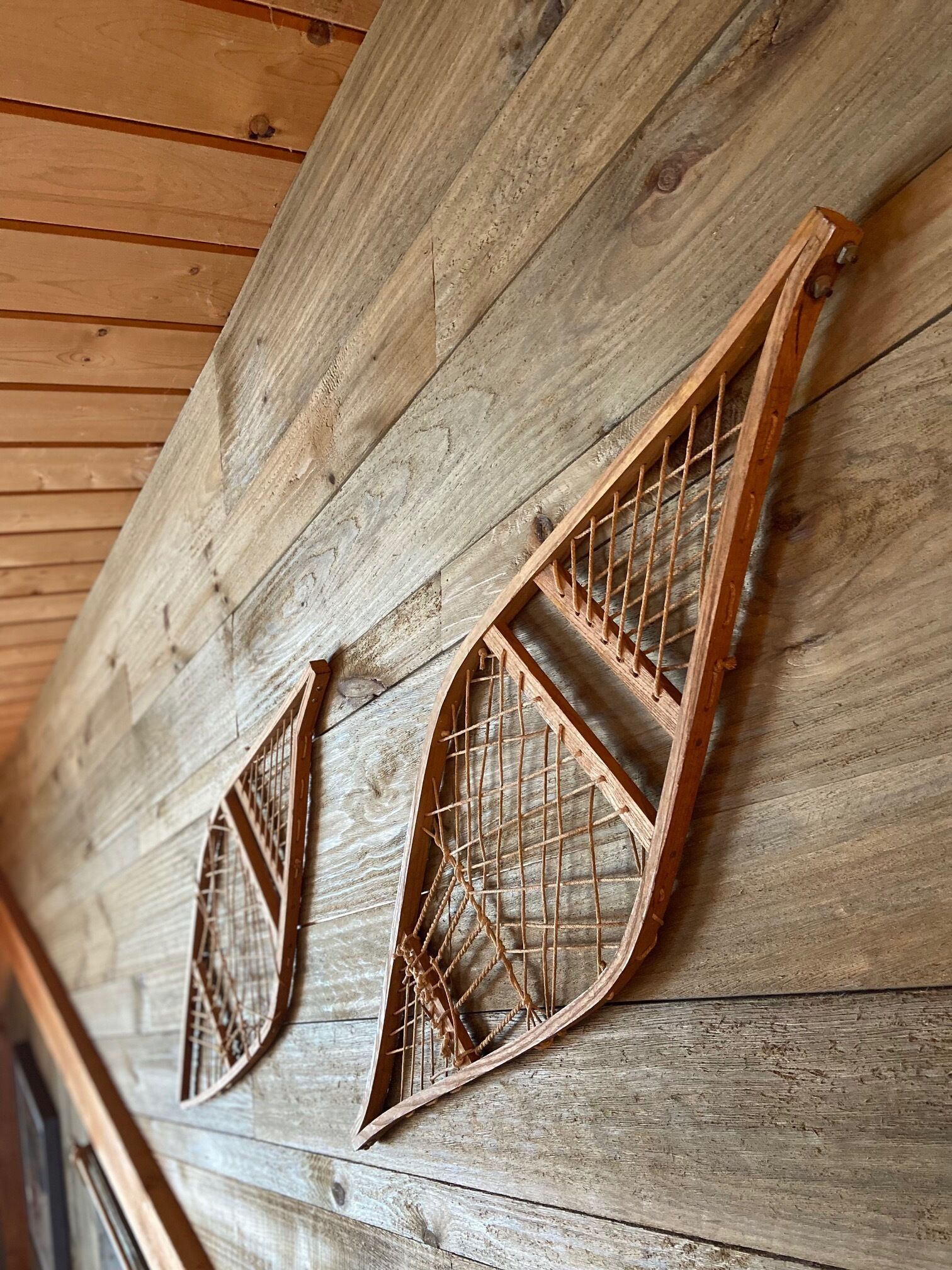 A wooden wall with two triangular windows featuring a grid pattern.