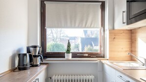 Una cocina compacta con ventana, radiador y electrodomésticos modernos.