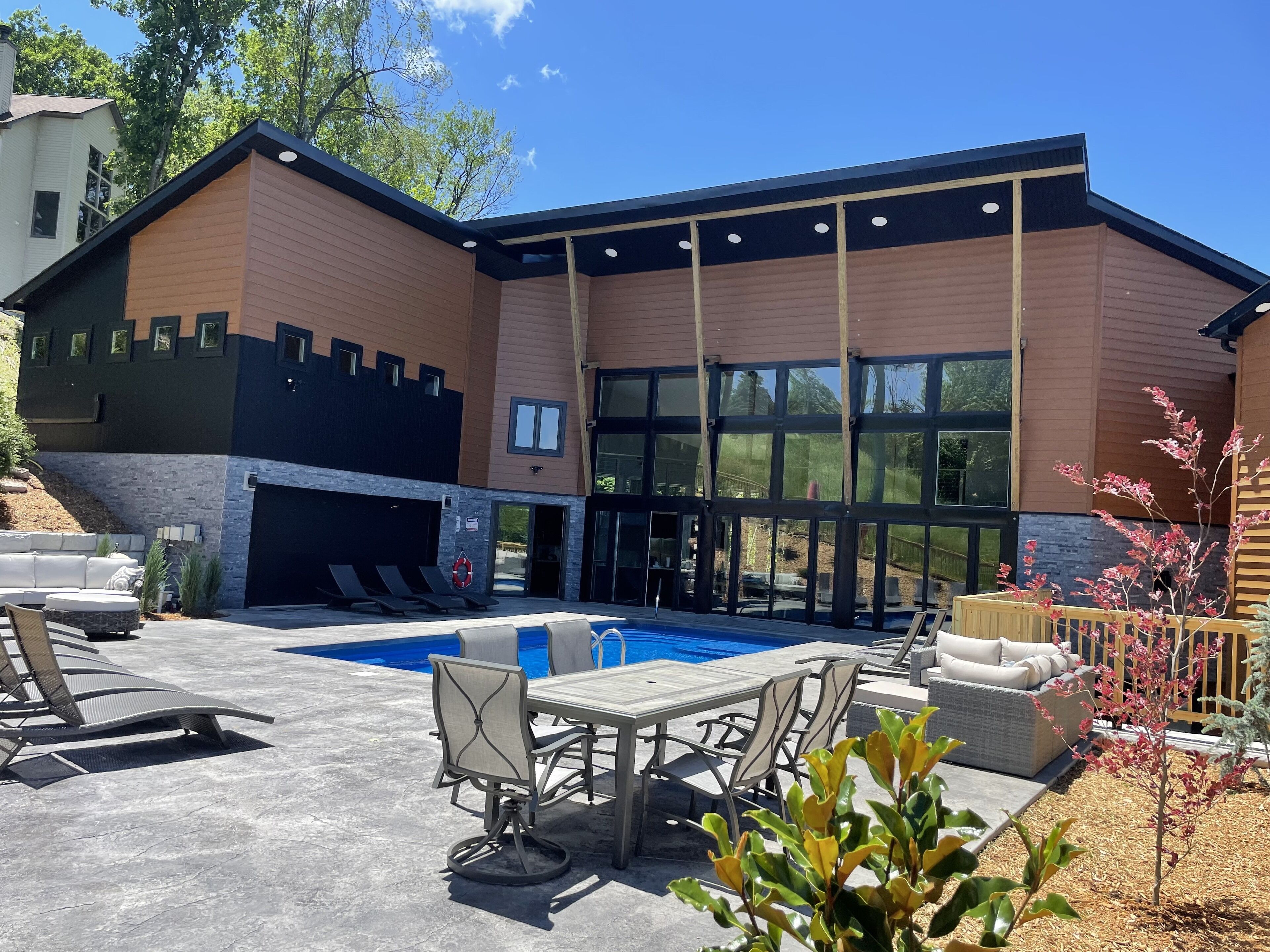 A modern house with a swimming pool, outdoor seating, and large windows.