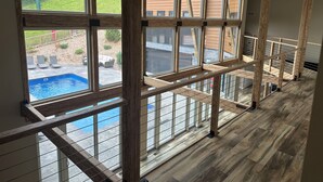 A spacious room with large windows overlooking a backyard with a pool and outdoor furniture.