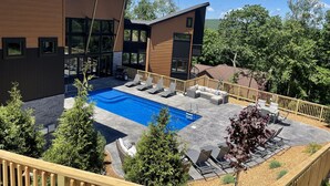 A modern house with a swimming pool, outdoor seating, and a wooden deck.