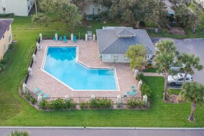 A swimming pool with a geometric shape, surrounded by a paved deck and lounge chairs. - Topsail at Schooner Court (St. Augustine Beach)