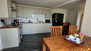 Una cocina moderna con armarios blancos, una mesa de comedor de madera y un refrigerador negro.
