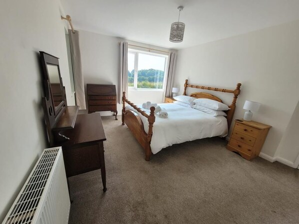A bedroom with a wooden bed, a bedside table, a dresser, a mirror, and a radiator. - Quintessential, secluded South Devon cottage (Plymouth, Devon)
