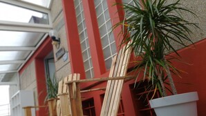 Une chaise en bois et une plante en pot, dans un intérieur avec un sol carrelé et un mur rouge.