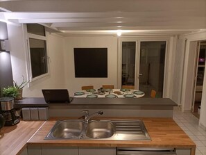 Una cocina moderna con encimera de madera, un lavabo doble y una zona de comedor con mesa y sillas.
