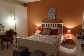 Un dormitorio con cama, mesitas de noche, un escritorio y una silla.
