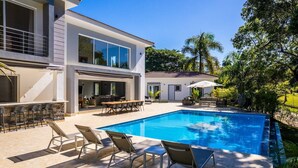 Une maison moderne dotée d’une piscine, d’un espace salon extérieur et d’un patio.