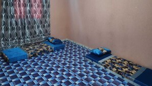 A room with a checkered floor, a patterned curtain, and blue cushions. - Corporate Apartment (Nouakchott)