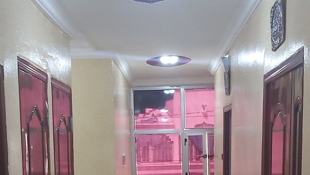 A hallway with marble flooring, wooden doors, and a ceiling light fixture. - Corporate Apartment (Nouakchott)