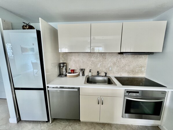 Una cocina moderna con lavavajillas integrado, electrodomésticos de acero inoxidable y salpicadero de mármol.