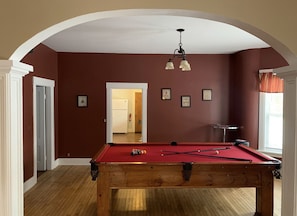 A pool table in a room with red walls and a wooden floor.