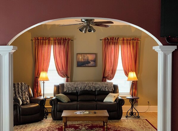A living room with a sofa, armchairs, a coffee table, and two lamps.