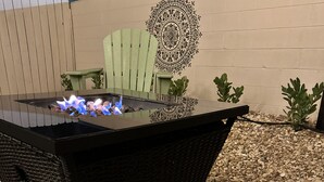 A black outdoor table with a built-in fire feature, surrounded by pebbles.