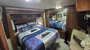 Een slaapkamer met een bed, een spiegel, een dressoir en een raam.