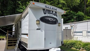 Een witte camper met de naam "Salem Villa Classic" en nummer 323. Het heeft een ladder en een witte watertank.