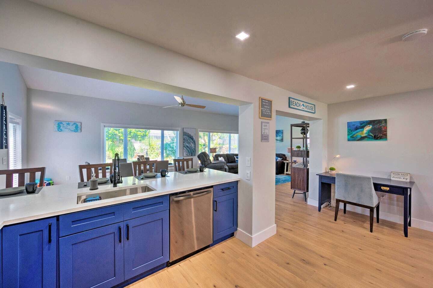 Een moderne keuken met blauwe kastjes, een vaatwasser en een eethoek met een tafel en stoelen.