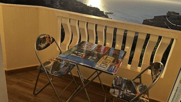 A balcony with a table and chairs, overlooking a coastal cityscape during sunset. - Apartment in perfect condition sea view (Rais Hamidou)