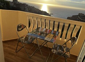 A balcony with a table and chairs, overlooking a coastal cityscape during sunset. - Apartment in perfect condition with a view of the ocean (Rais Hamidou)
