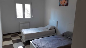 A room with two single beds, a radiator, and a checkered floor. - Apartment in perfect condition sea view (Rais Hamidou)