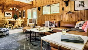 A wooden cabin interior with a dining area, a sofa, and a table with drinks. - 5BR/5BA Cabin, Sleeps 14, Hot Tub/Game Rm, Pool Close, 5min to G'burg/Nat'l Park (Gatlinburg)