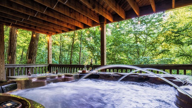 A hot tub with a wooden deck and a view of a forest. - 5BR/5BA Cabin, Sleeps 14, Hot Tub/Game Rm, Pool Close, 5min to G'burg/Nat'l Park (Gatlinburg)