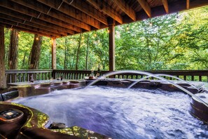Ein Whirlpool mit Holzterrasse und Blick auf einen Wald.