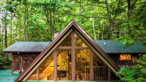 A cabin with a steeply pitched roof, large windows, and a stone facade. - 5BR/5BA Cabin, Sleeps 14, Hot Tub/Game Rm, Pool Close, 5min to G'burg/Nat'l Park (Gatlinburg)