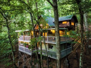 A multi-story cabin with balconies, surrounded by trees.
