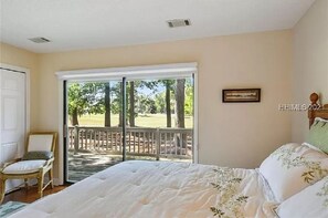 Relax in this serene bedroom with a large bed, a comfortable chair, and access to an outdoor area.