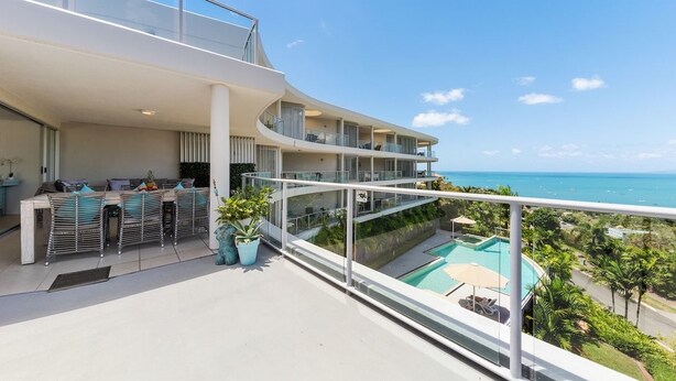 Un balcon moderne d’hôtel avec piscine, espace salon et vue sur l’océan.
