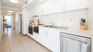 Une cuisine moderne avec des meubles blancs, un lave-vaisselle, un four à micro-ondes et un évier.