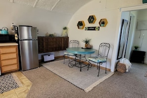 Compact kitchen area with a refrigerator, microwave, and dining table for two.