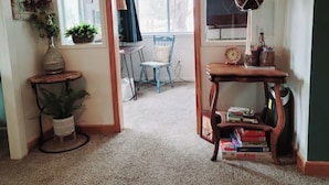 A cozy living room with a wooden coffee table, a bookshelf, and a hanging plant. - Lakeside Quonset Hut, Cozy And Romantic (Paw Paw)