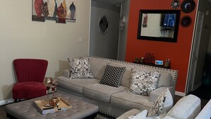 Uma sala de estar com sofá, poltronas, mesa de centro e televisão.