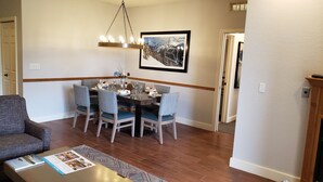 A dining area with a wooden table, six chairs, and a chandelier. - Winter Ski Holiday at Boyne Mountain - Cozy Luxury Villa (Boyne Falls)