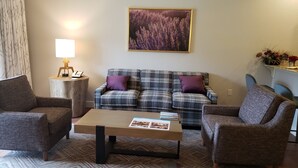 A living room with a plaid sofa, two armchairs, a coffee table, a lamp, and a framed picture on the wall. - Winter Ski Holiday at Boyne Mountain - Cozy Luxury Villa (Boyne Falls)