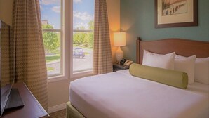 A hotel room with a bed, a desk, a lamp, and a window with curtains. - Winter Ski Holiday at Boyne Mountain - Cozy Luxury Villa (Boyne Falls)