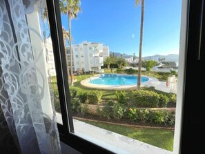 A view of a swimming pool surrounded by greenery and buildings. - Sea-view apartment in Torrecilla (Nerja)