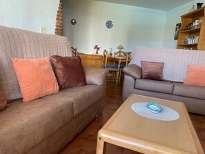 Un salon avec deux canapés, une table basse et, au fond, un coin repas.