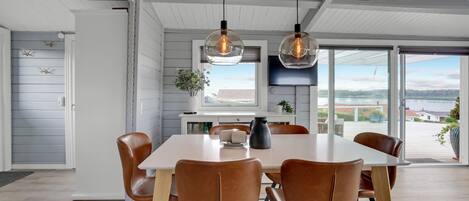 A modern dining area with a white table, brown leather chairs, and pendant lights.