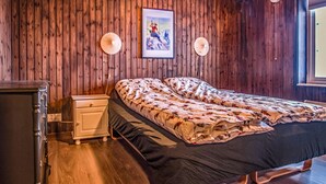 Une chambre à coucher aux murs lambrés, avec un lit, une table de chevet et un tableau encadré accroché au mur.