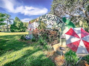 A sign for Gulfport with a historical marker and a large umbrella sculpture.