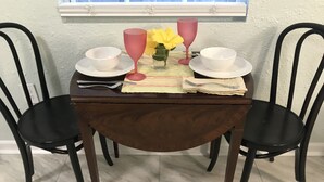 Une table à manger dressée avec de l’assiette blanche, des verres à vin roses et un vase rempli de fleurs jaunes.